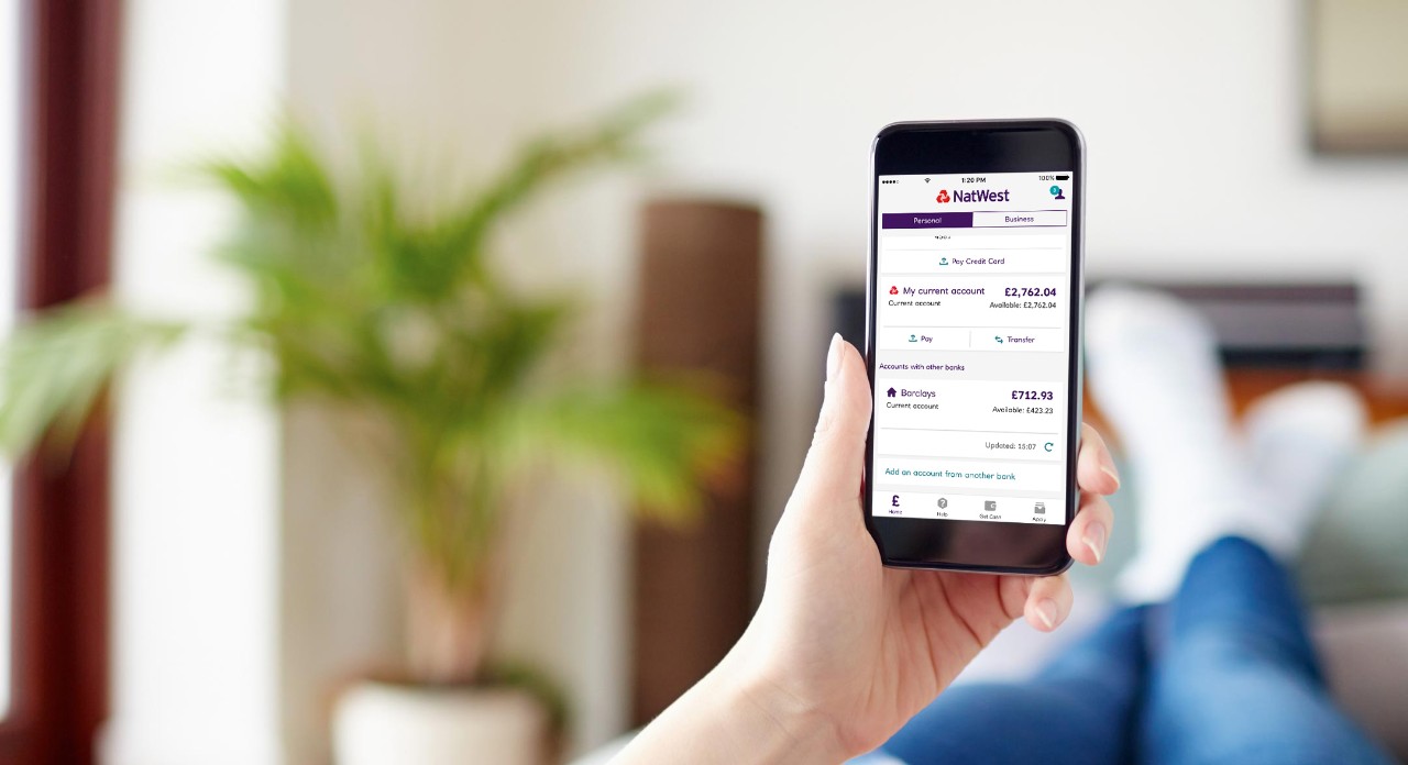 Photograph of someone holding a phone with the NatWest mobile app
