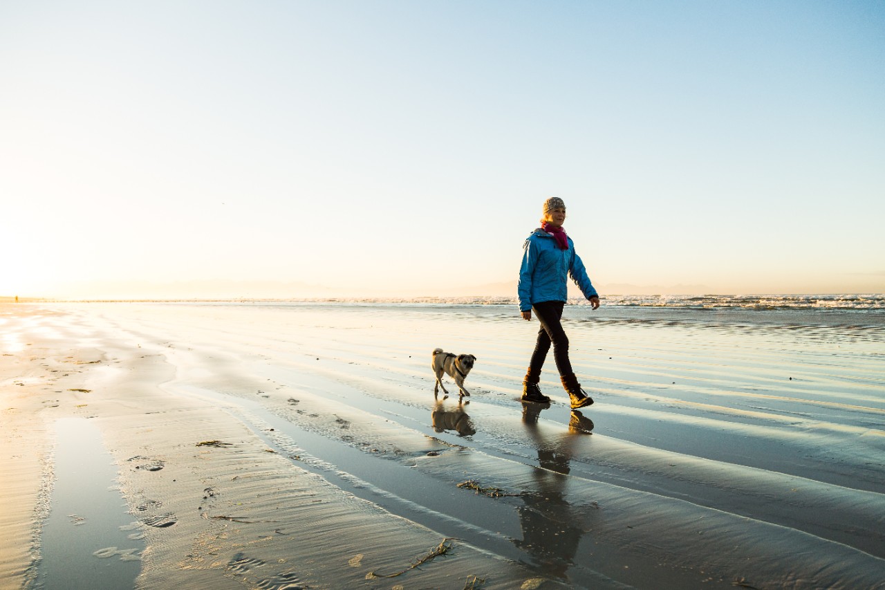 woman walking on a beach with a dog